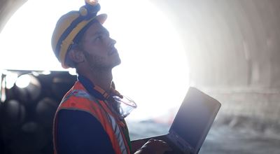 Construction worker with a laptop standing inside a tunnel