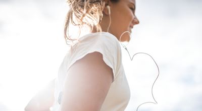 Young woman with insulin control patch on arm, out for a run listening to music