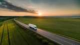 White truck on empy road surrounded by green fields