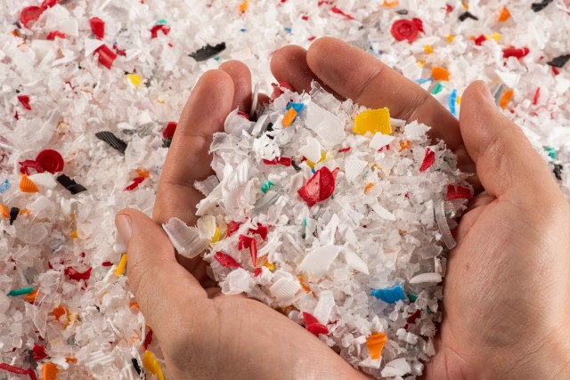 Two hands holding small pieces of plastic for recycling